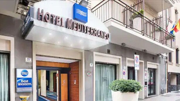Un hôtel appelé « HOTEL MEDIERRANO », avec une enseigne indiquant qu’il fait partie de la chaîne hôtelière Best Western.
