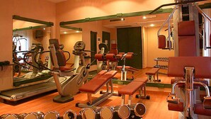 Une salle de sport équipée de machines d’exercice, de miroirs et d’un tapis de course.