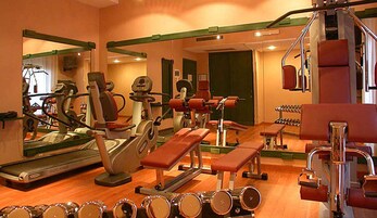 Un gimnasio con equipamiento de ejercicio, espejos y una cinta de correr.
