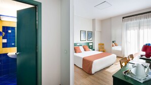 Une chambre d’hôtel avec un lit, un bureau doté d’une bouilloire, une chaise et une fenêtre avec des rideaux.