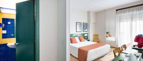 Una habitación de hotel con cama, escritorio con hervidor, silla y ventana con cortinas.