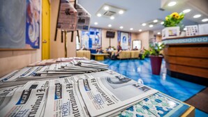 Un hall d’hôtel avec des journaux sur une table, un comptoir d’accueil et un sol bleu.