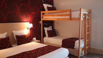 Une chambre avec un lit superposé, un papier peint à motifs de roses rouges, du linge de lit blanc et un plancher en bois.