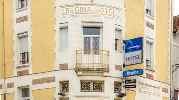 Un edificio con el letrero "REGINA HOTEL" y un balcón con barandilla de hierro forjado.