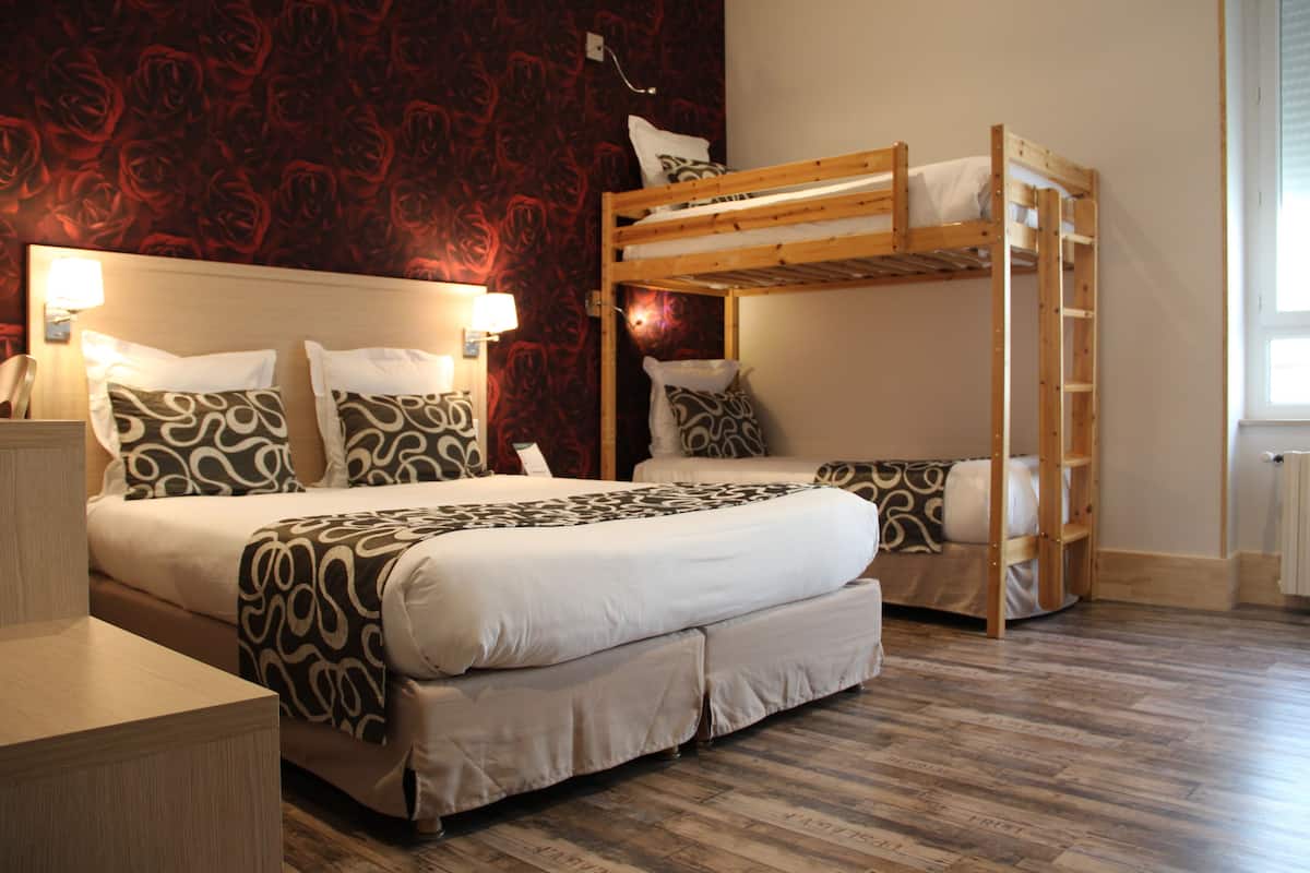 Een kamer met een stapelbed, een bureau en een bed met een patroon.