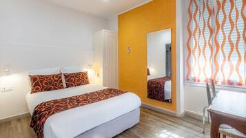 Une chambre d’hôtel avec un lit, un bureau et un miroir.