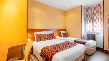 Une chambre d’hôtel avec deux lits, une tête de lit en bois, une fenêtre avec des rideaux orange et un radiateur.