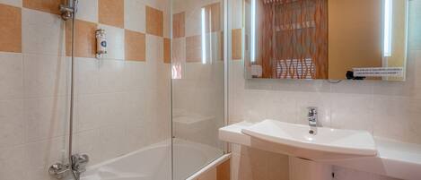 Un baño con ducha envuelta en vidrio, un lavabo blanco y un espejo encima.