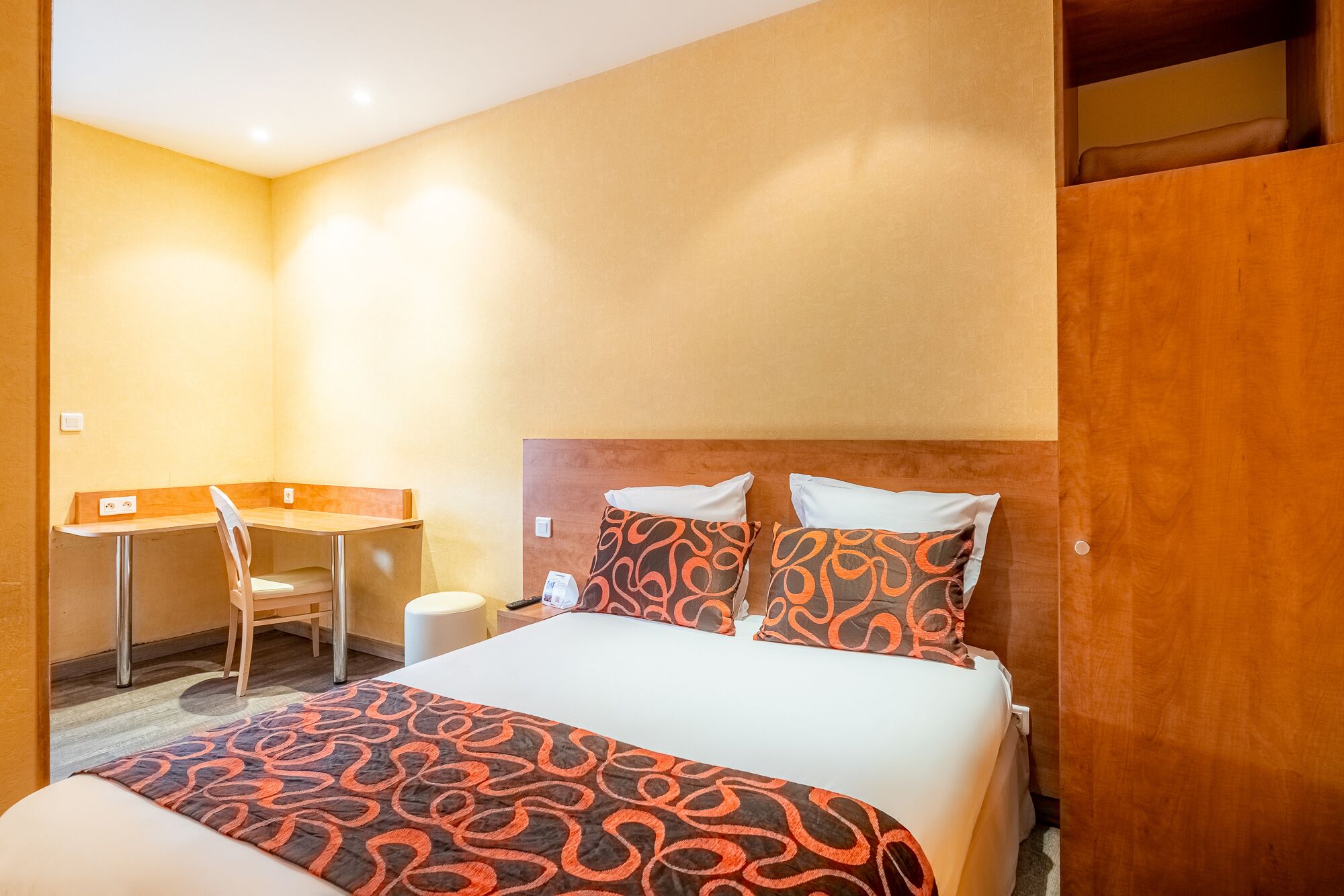 A hotel room with a bed, a desk, and a chair.