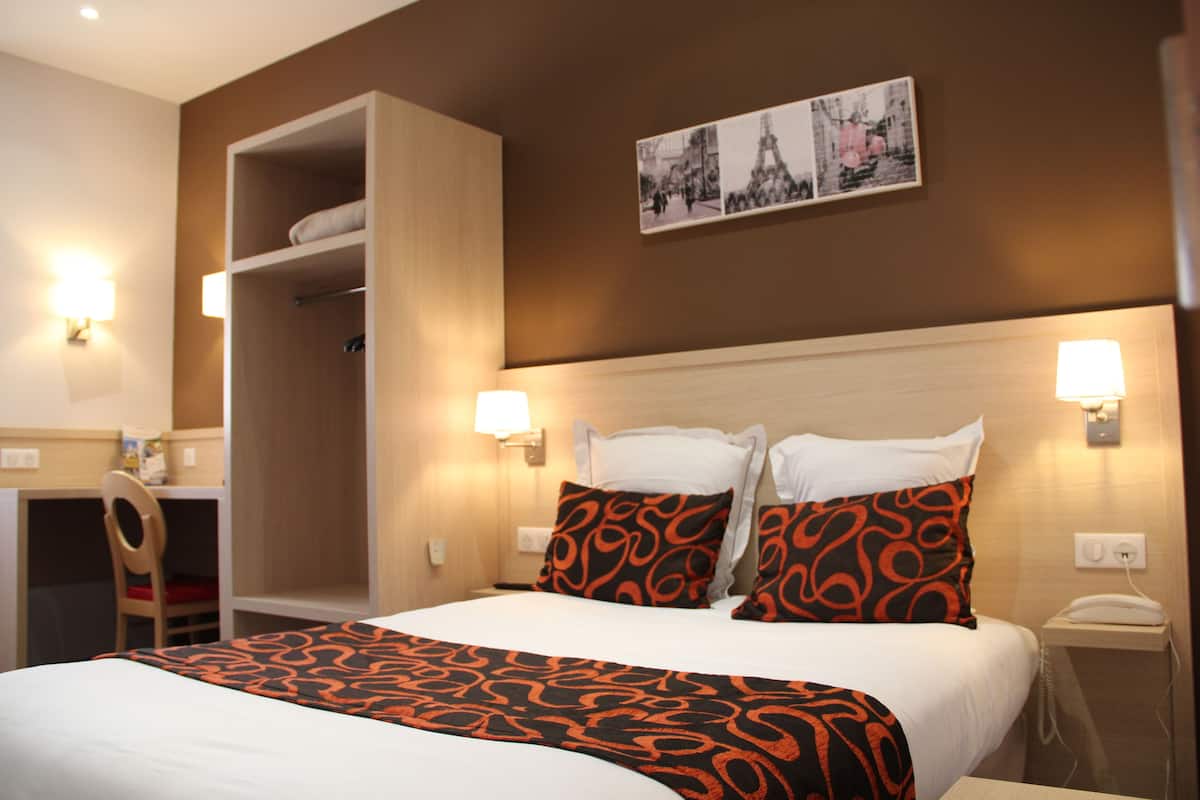 Een hotelkamer met een bed, een kledingkast, een bureau en een stoel.