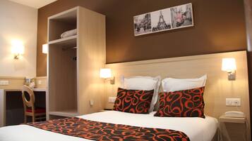 A hotel room with a bed, a wardrobe, a desk, and a chair.