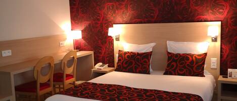 Habitación de hotel con cama, mesitas de noche, escritorio y sillas.