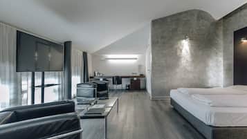 A modern hotel room with a large bed, a desk, and a seating area with chairs.