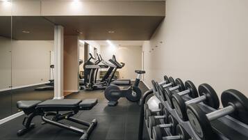 Un gimnasio con equipo de ejercicio, incluyendo cintas de correr, mancuernas y bancos de pesas.