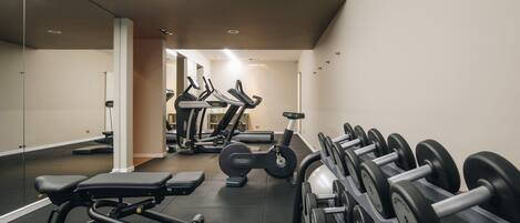A gym with exercise equipment, including treadmills, dumbbells, and weight benches.