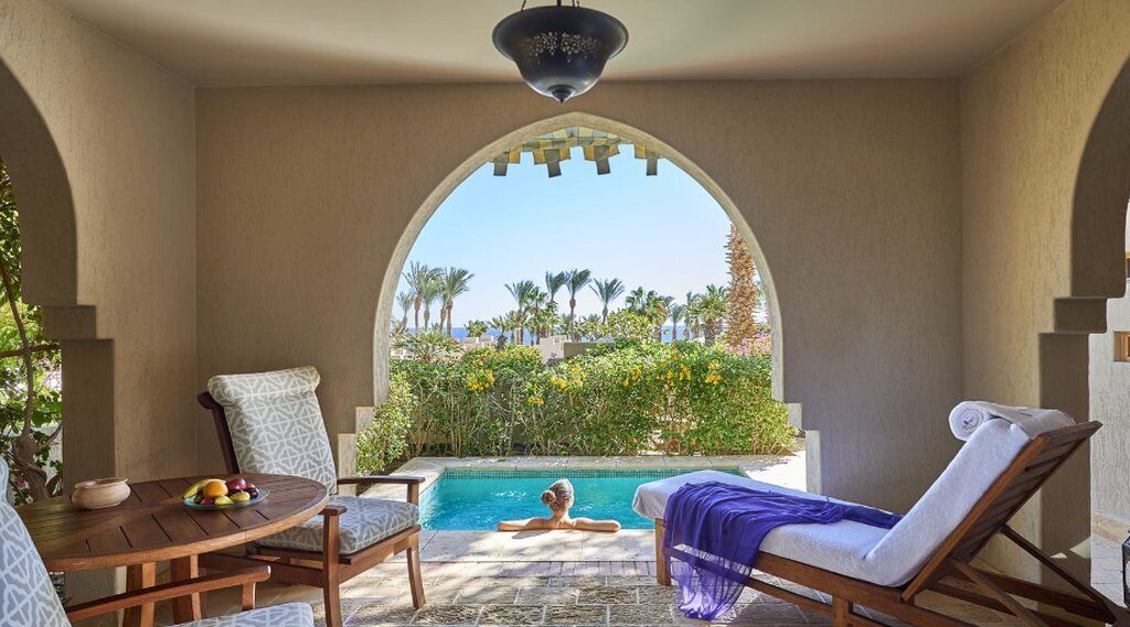 A poolside area with a view of palm trees and a clear sky.