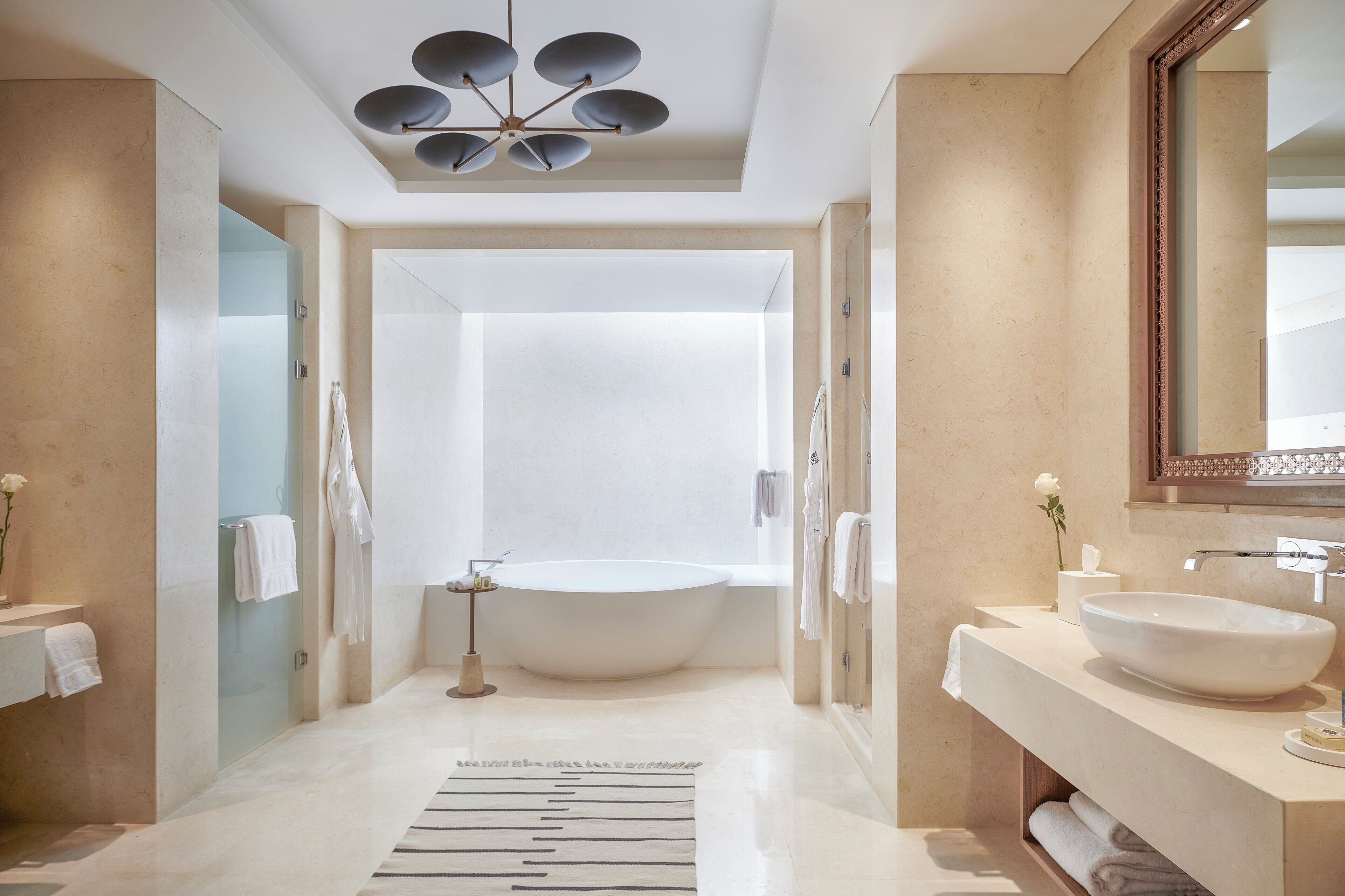 Un baño moderno con una bañera independiente, un espejo grande y un diseño minimalista.