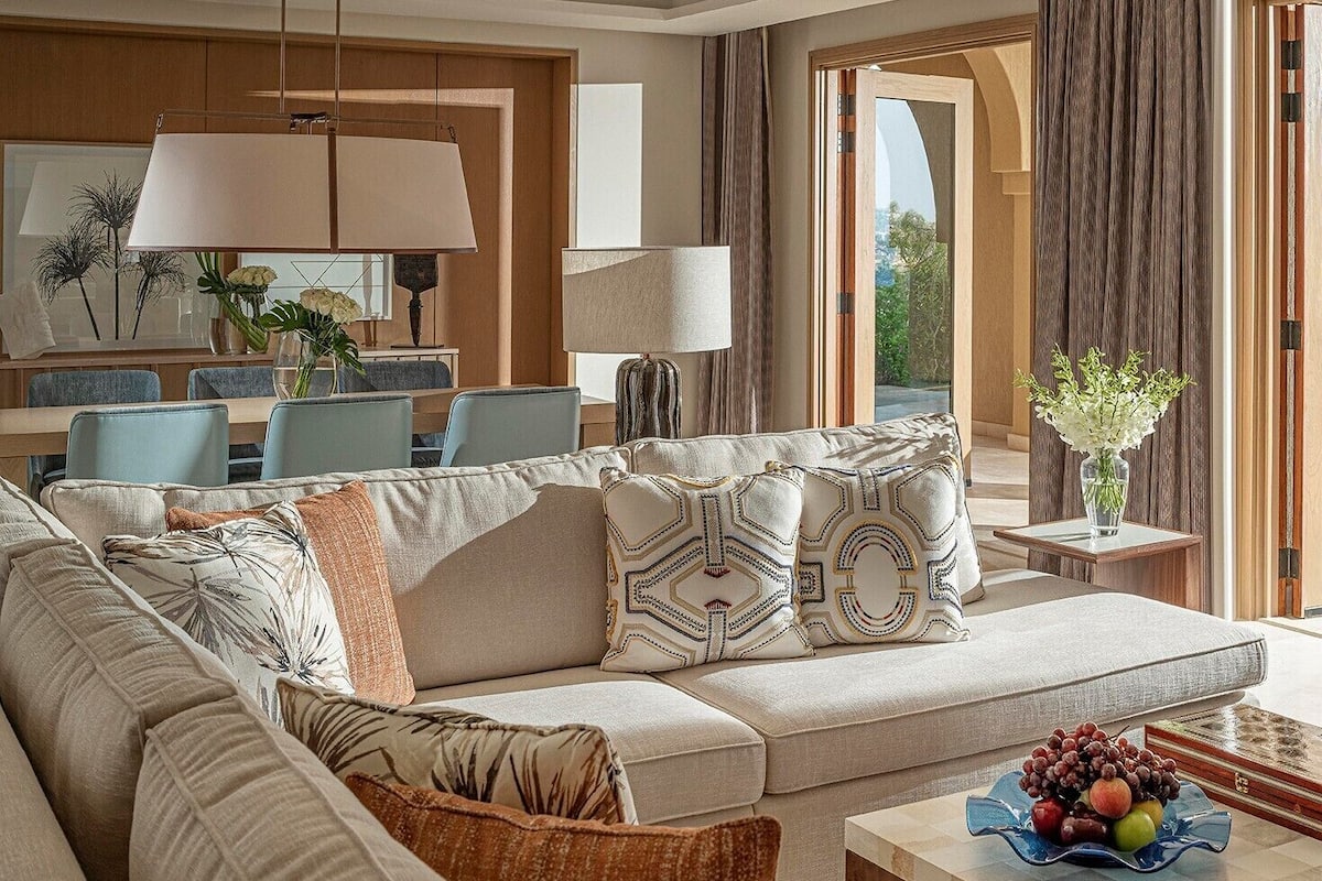 A modern living room with a sofa, side tables, and a dining area.