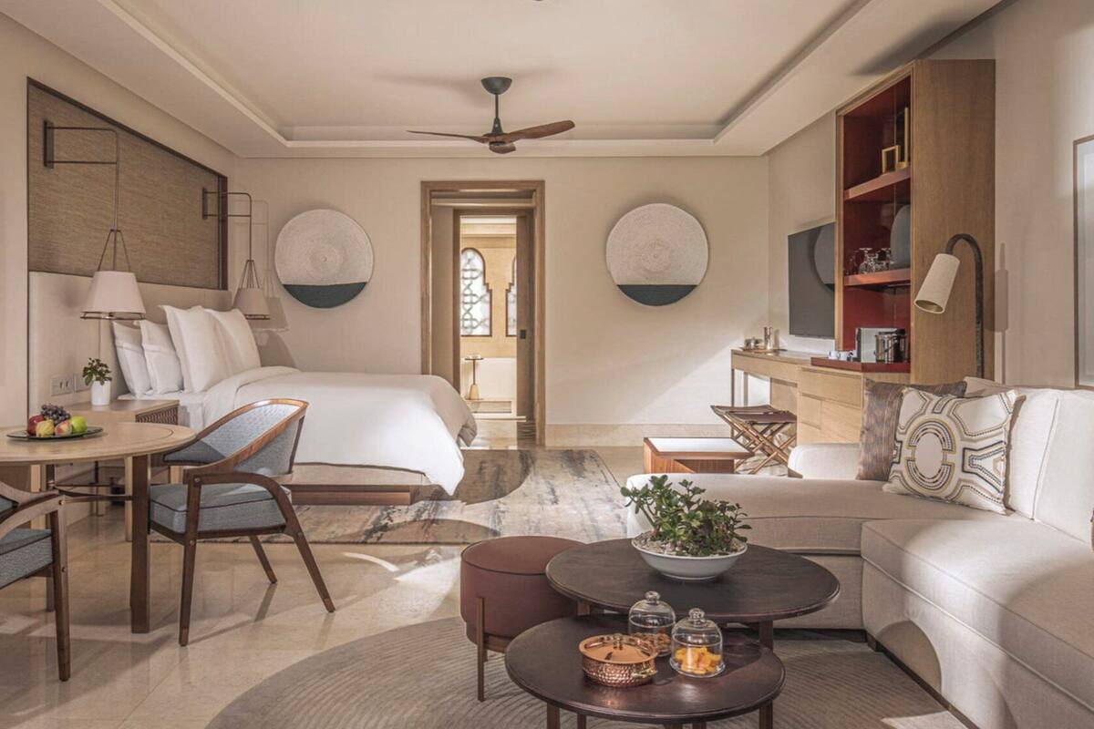 A modern hotel room with a bed, a desk, a sofa, and a dining area.