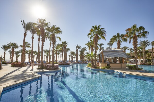 A swimming pool with palm trees and a gazebo, surrounded by lounge chairs and a clear sky. - Four Seasons Resort Sharm EL Sheikh (Sharm El Sheikh)
