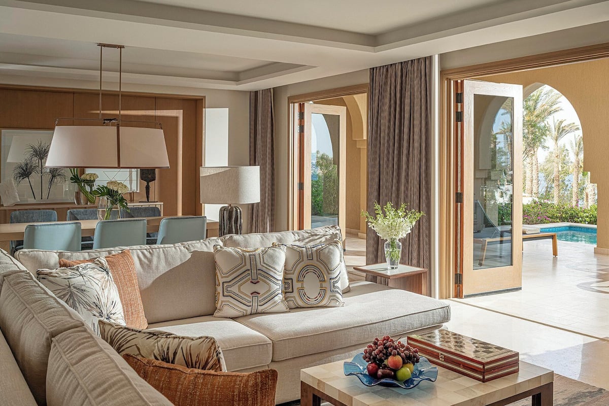 A spacious living room with a sofa, coffee table, and a view of a pool.
