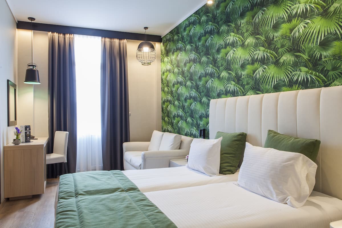 Ein Hotelzimmer mit Bett, Schreibtisch, Stuhl und einem großen Fenster mit Vorhängen.