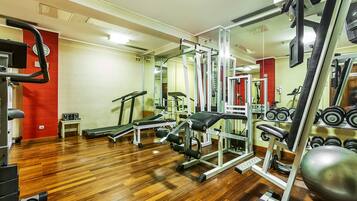 A gym with exercise equipment, a treadmill, and a mirror.