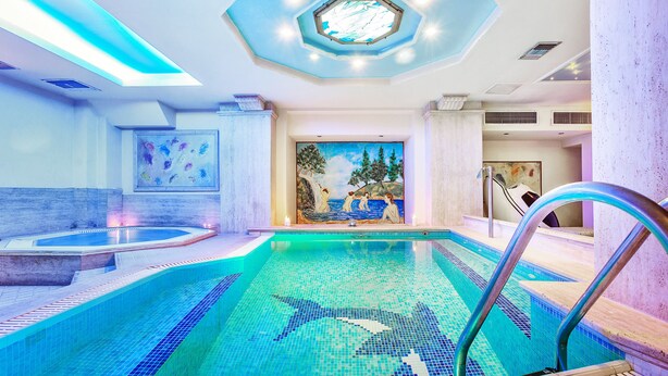 Ein Schwimmbecken mit einem Hai-Mosaik, einer Whirlpool und einer Wandmalerei mit Strandmotiv.