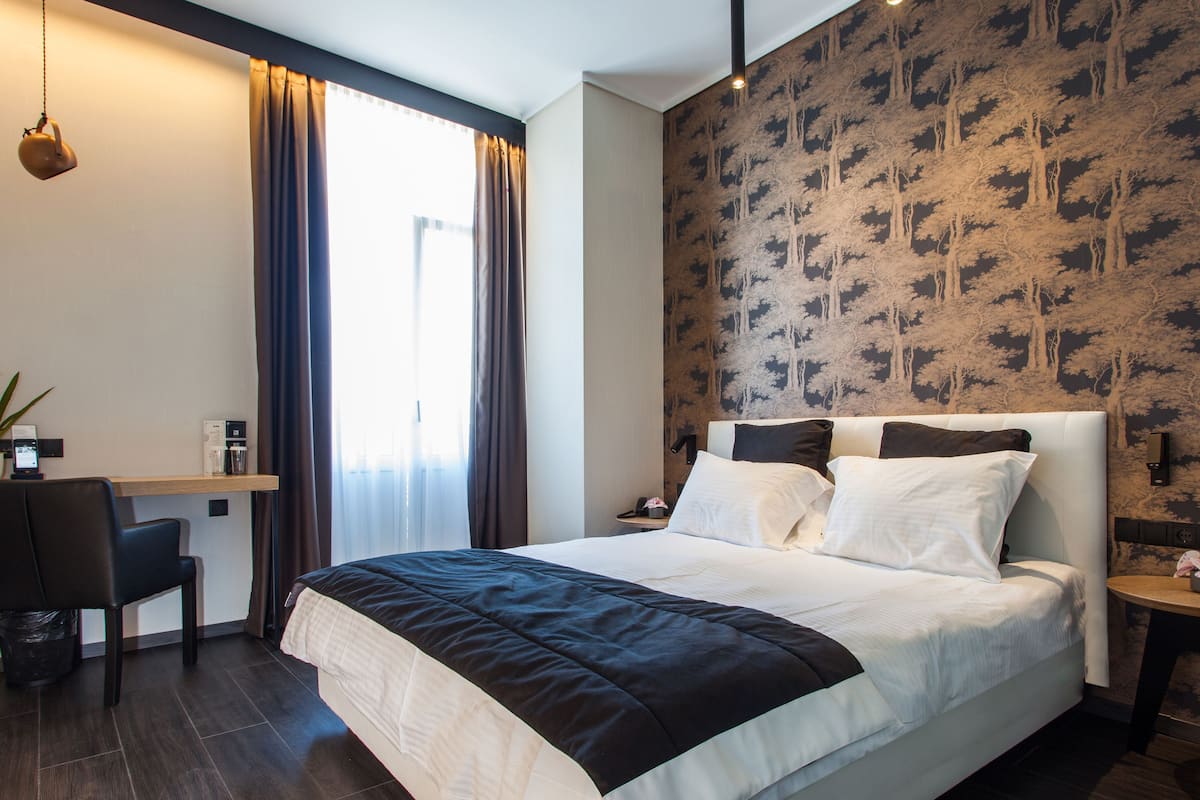 Ein Hotelzimmer mit Bett, Schreibtisch, Stuhl und kleinem Tisch.