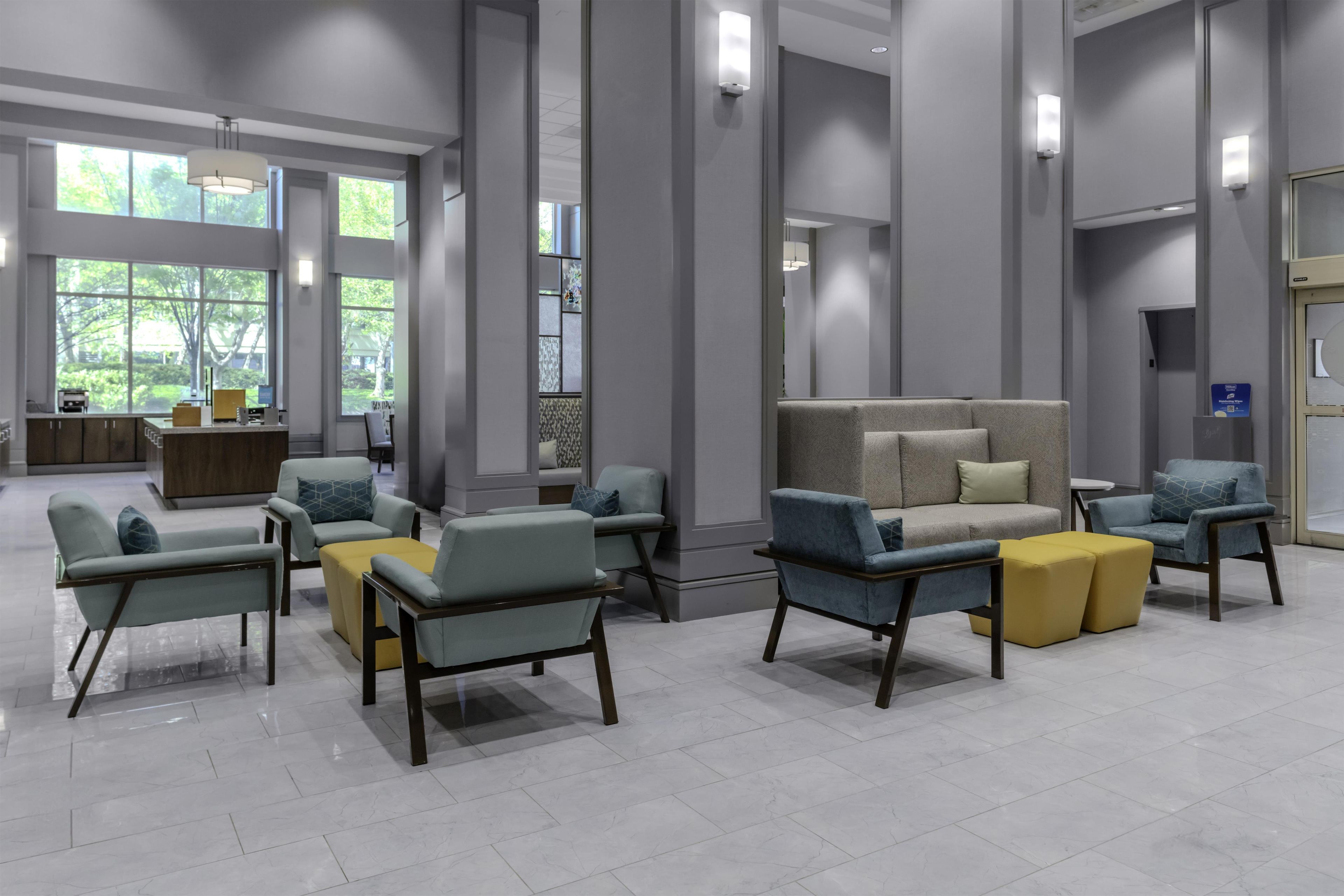 Um hall amplo com assentos modernos, janelas grandes e um balcão de recepção.