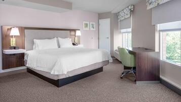 A hotel room with a large bed, bedside lamps, a desk, and a chair.