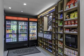 A snack and beverage vending area with various products and a microwave. - Hampton Inn & Suites Arlington Crystal City DCA (Arlington)