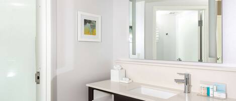 Une salle de bain moderne avec un lavabo blanc, un meuble-lavabo foncé et un grand miroir.