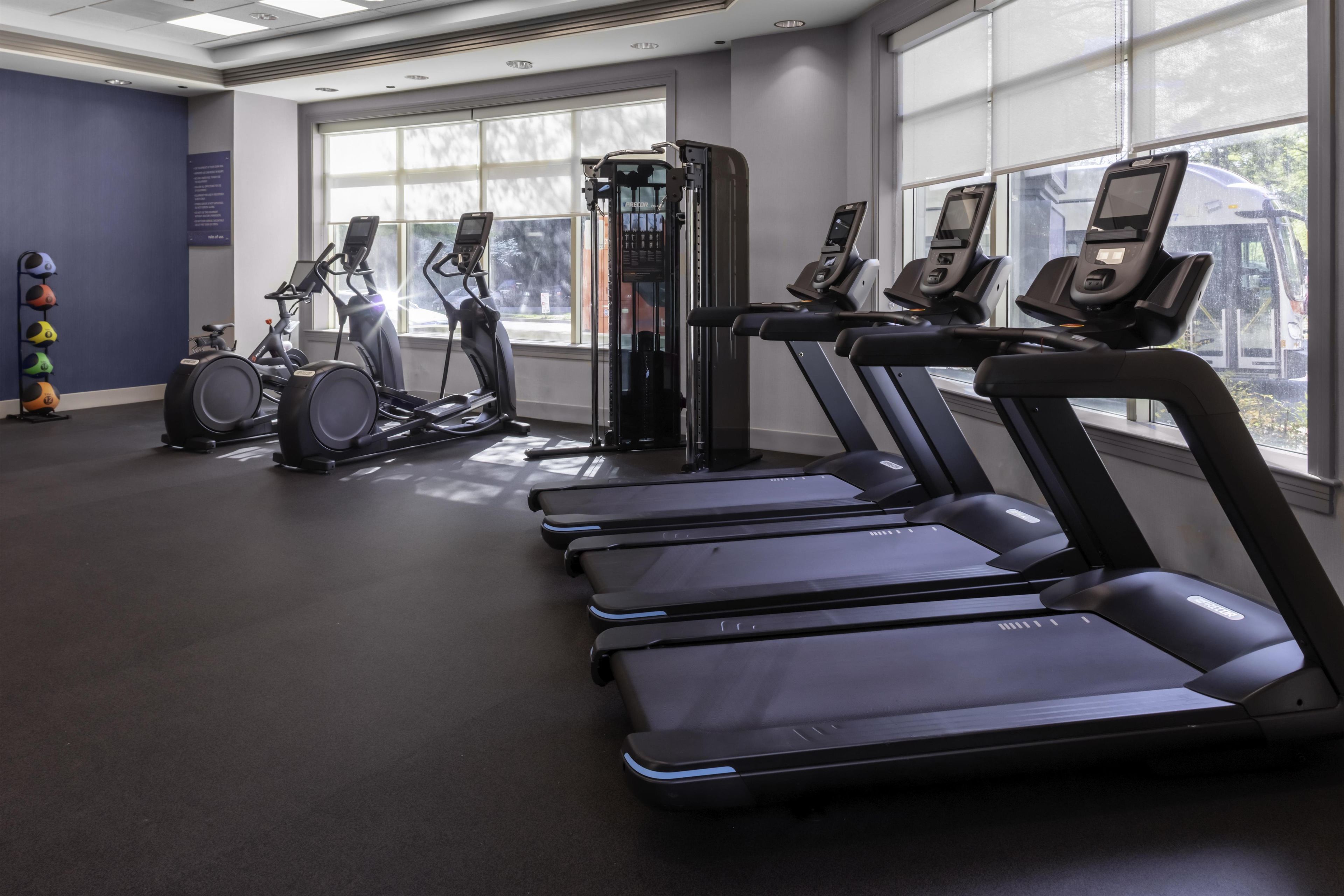 Un gimnasio con cintas de correr, bicicletas estáticas y máquinas de pesas.