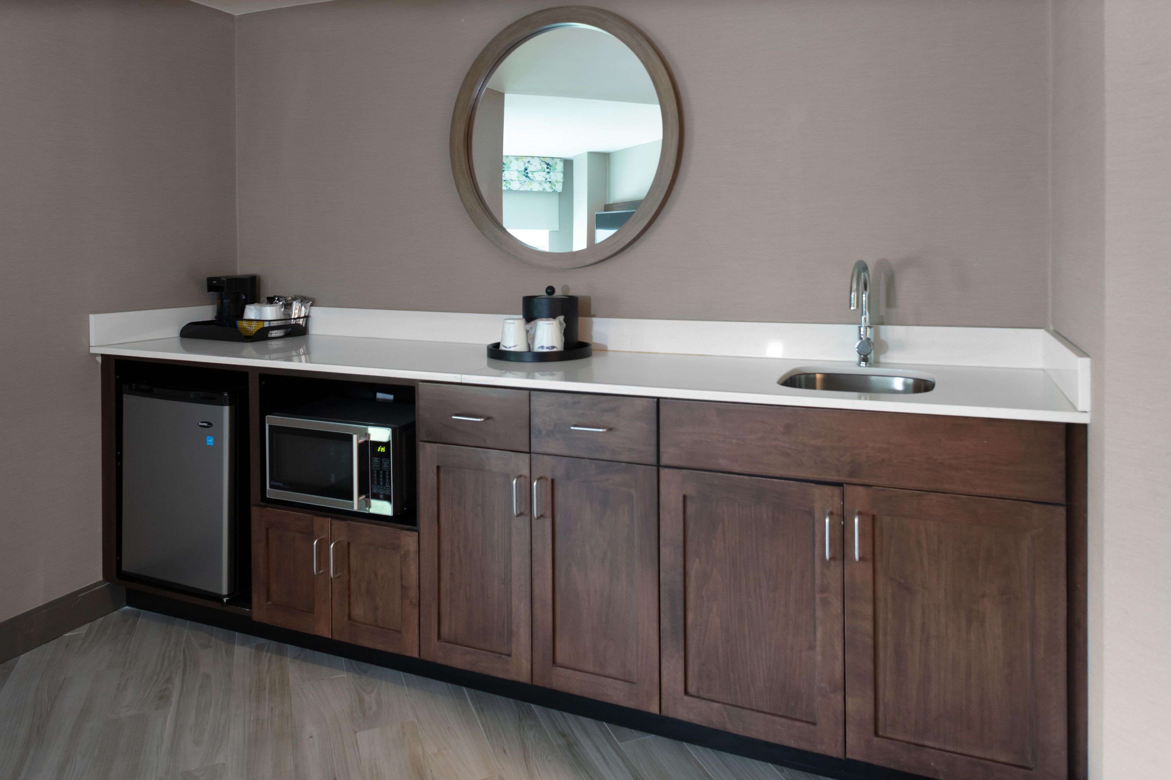 Una kitchenette equipada con microondas, cafetera y lavabo.