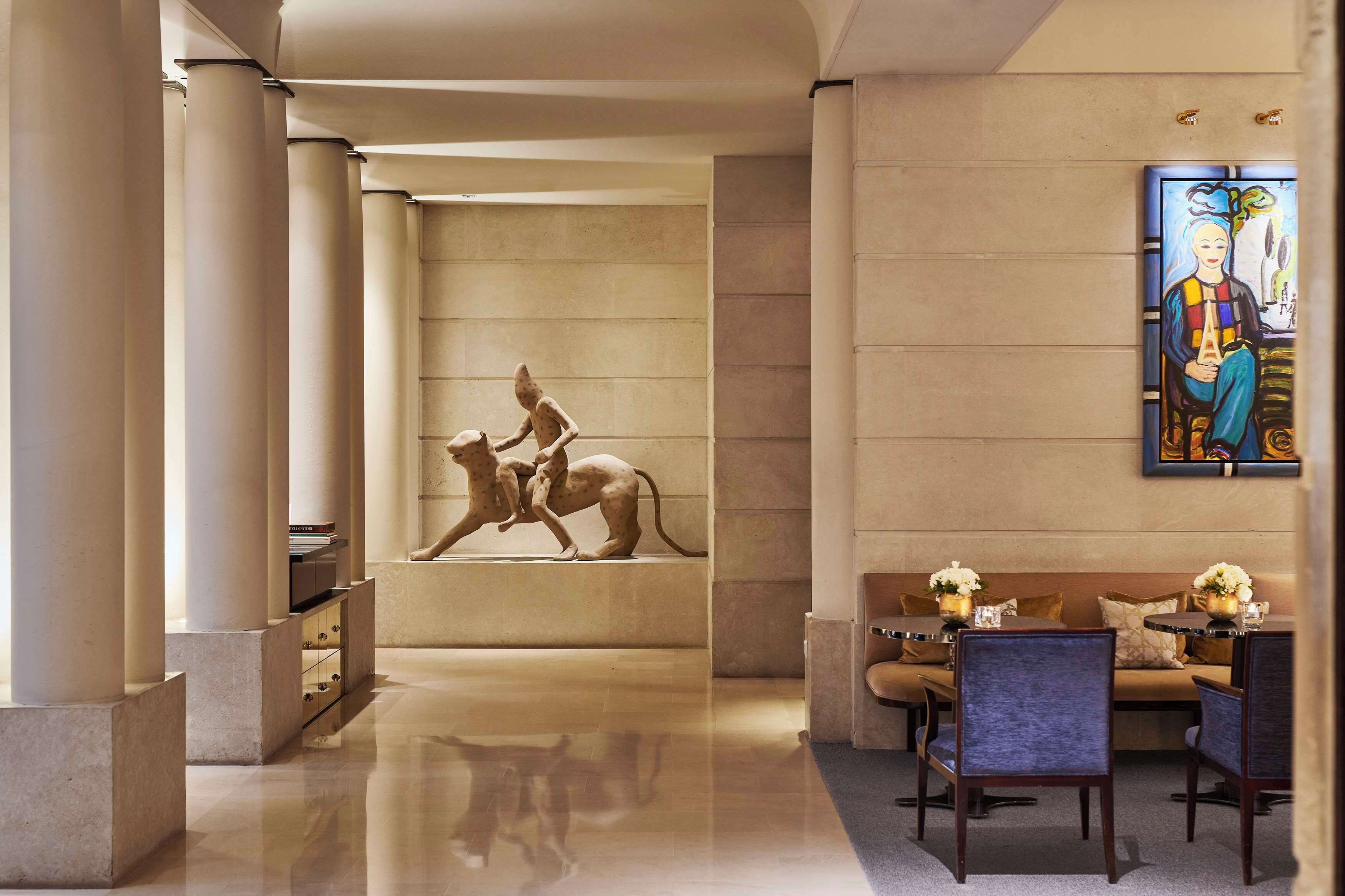 A lobby with a marble floor, a sculpture of a dog, a sofa, and a table with flowers.