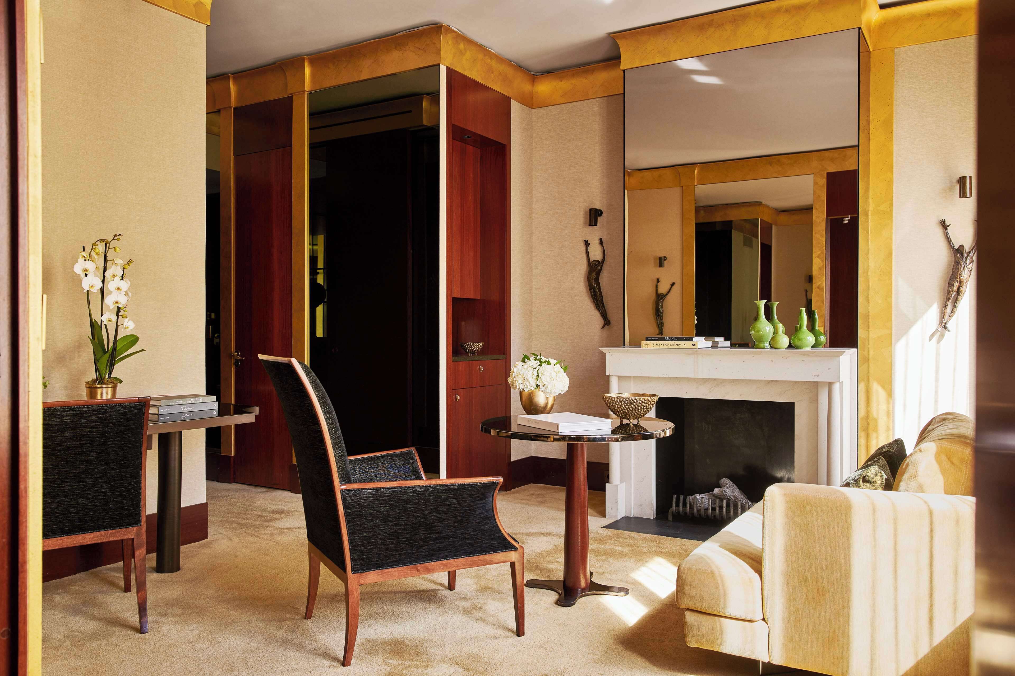 Una habitación con chimenea, espejo y zona de estar con sofá y sillones.