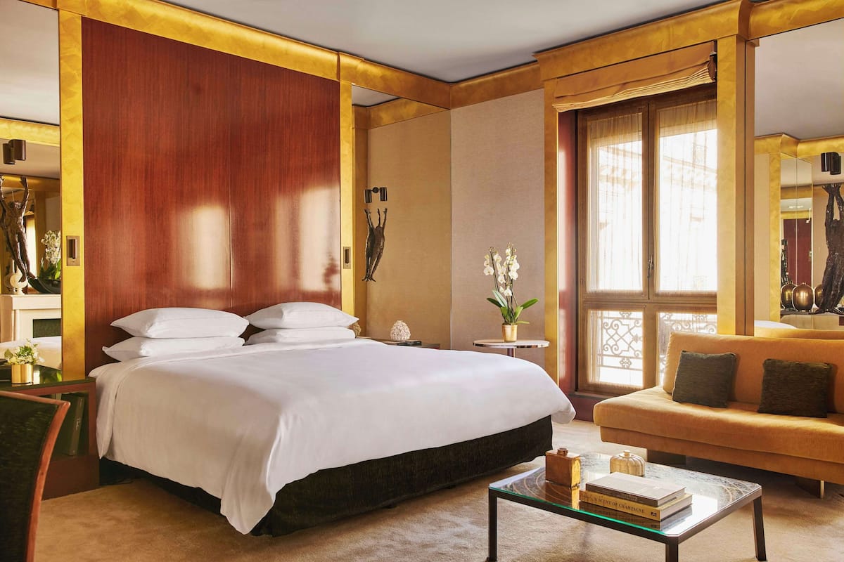 Ein Hotelzimmer mit einem großen Bett, einem Schlafsofa, einem Couchtisch und einem Fenster mit Vorhängen.