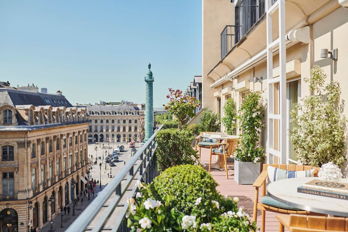 Ein Balkon mit Blick auf ein historisches Gebäude, einen Turm und eine Straße mit Fußgängern.