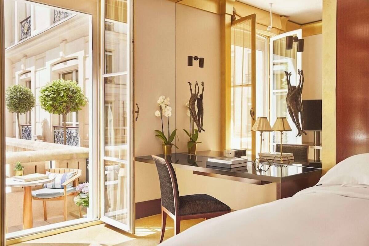 Ein Hotelzimmer mit Bett, Schreibtisch, Stuhl, Spiegel und Blick auf den Außenbalkon.