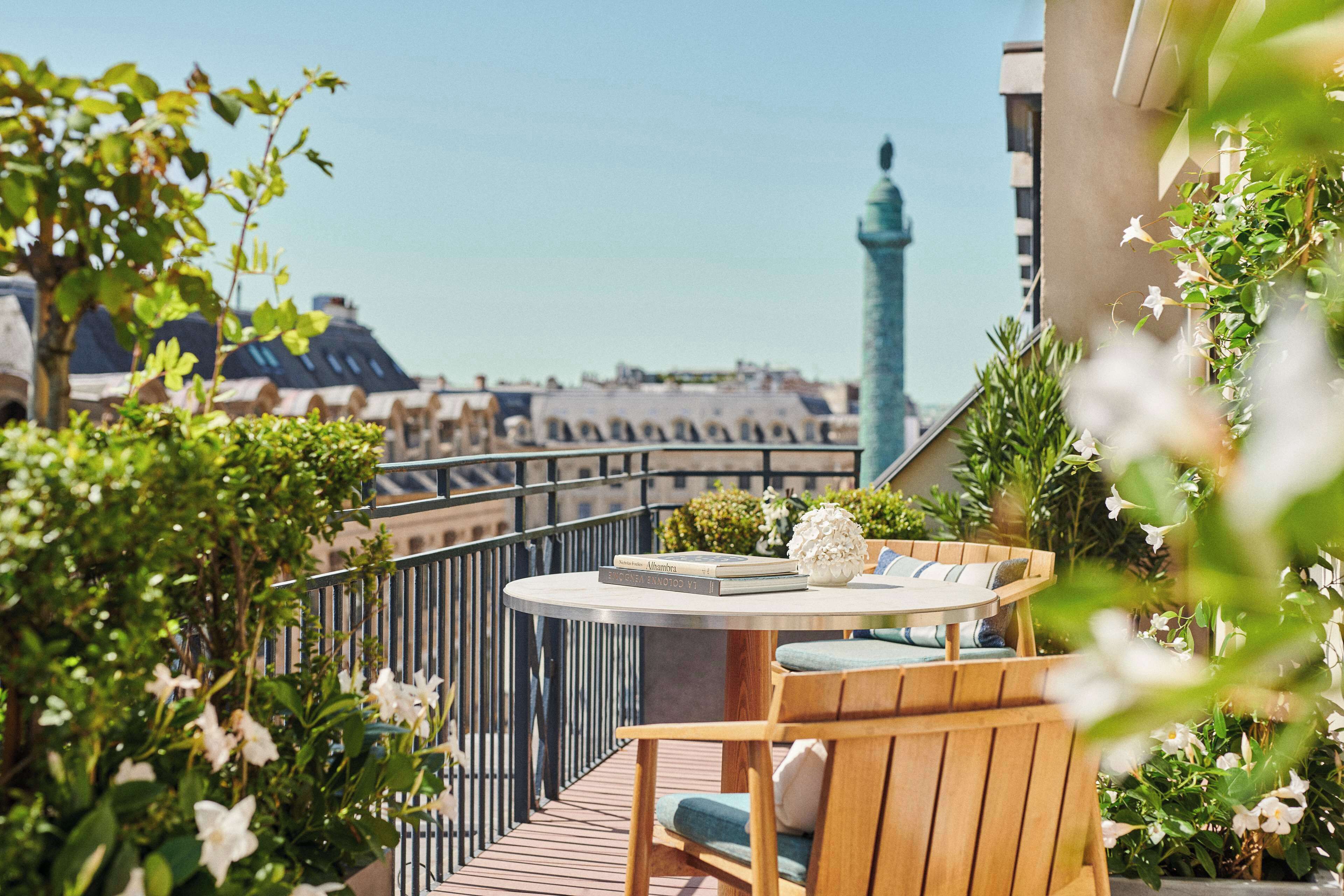 Un balcon avec une table ronde, une chaise en bois et des plantes en pot.