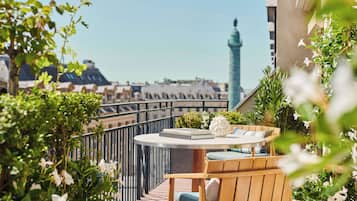 Un balcon avec une table ronde, une chaise en bois et des plantes en pot.