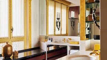 A bathroom with a large mirror, a white sink, and a vanity with a gold-colored cabinet.
