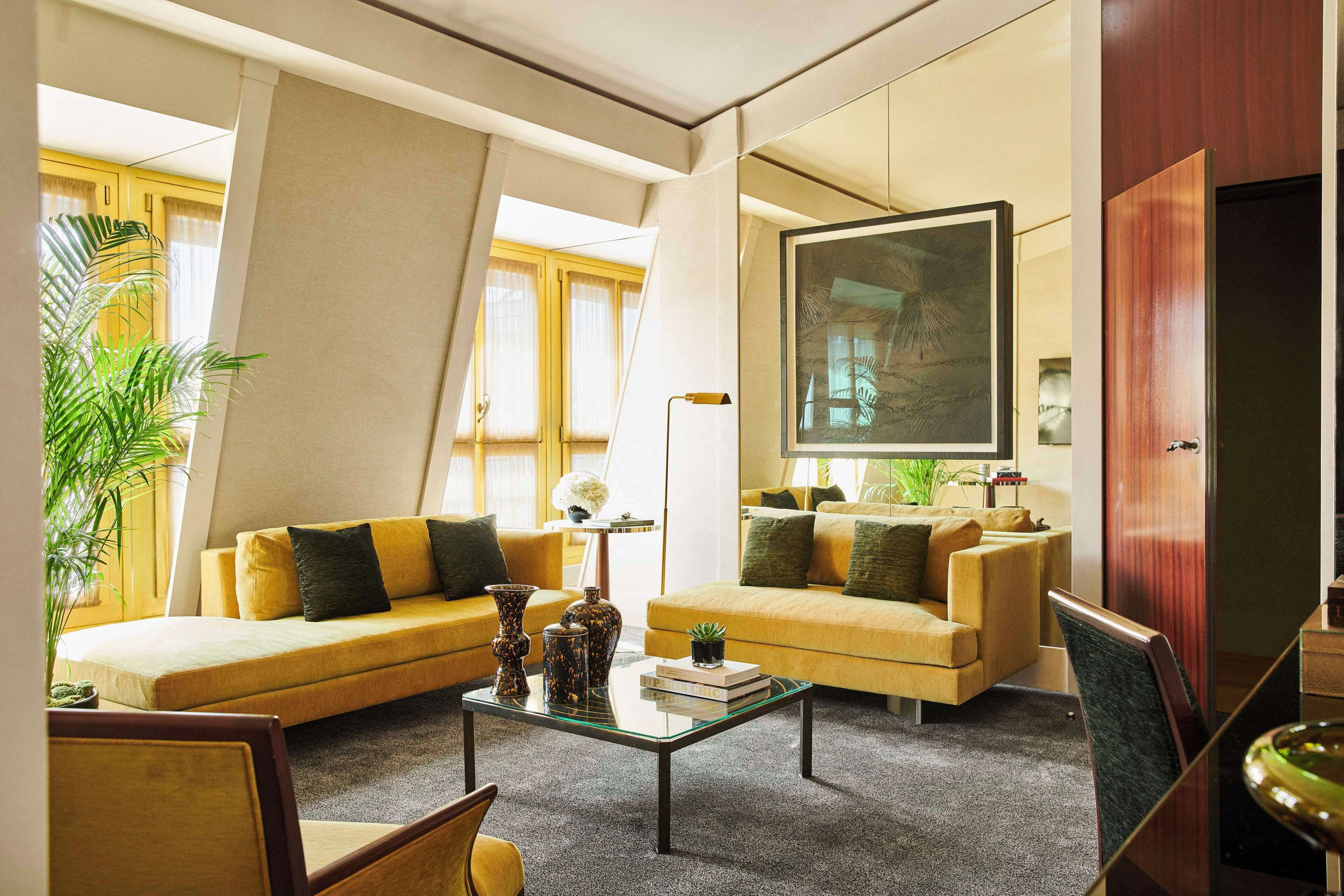 A modern living room with a sofa, armchairs, a coffee table, and a large mirror.