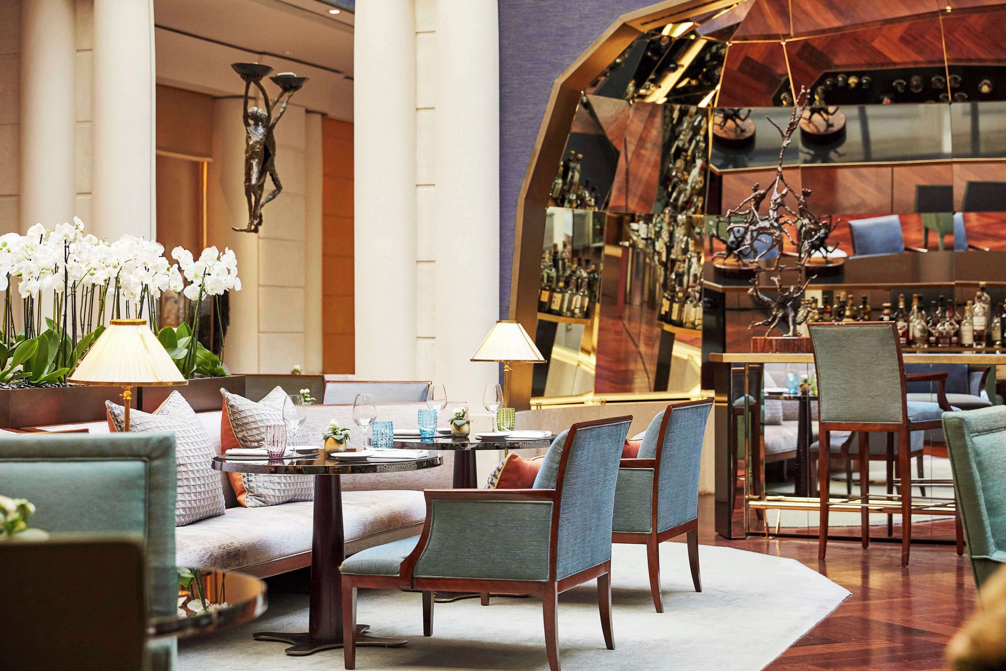 Un moderno vestíbulo de hotel con zona de bar, arreglos de asientos y detalles decorativos.