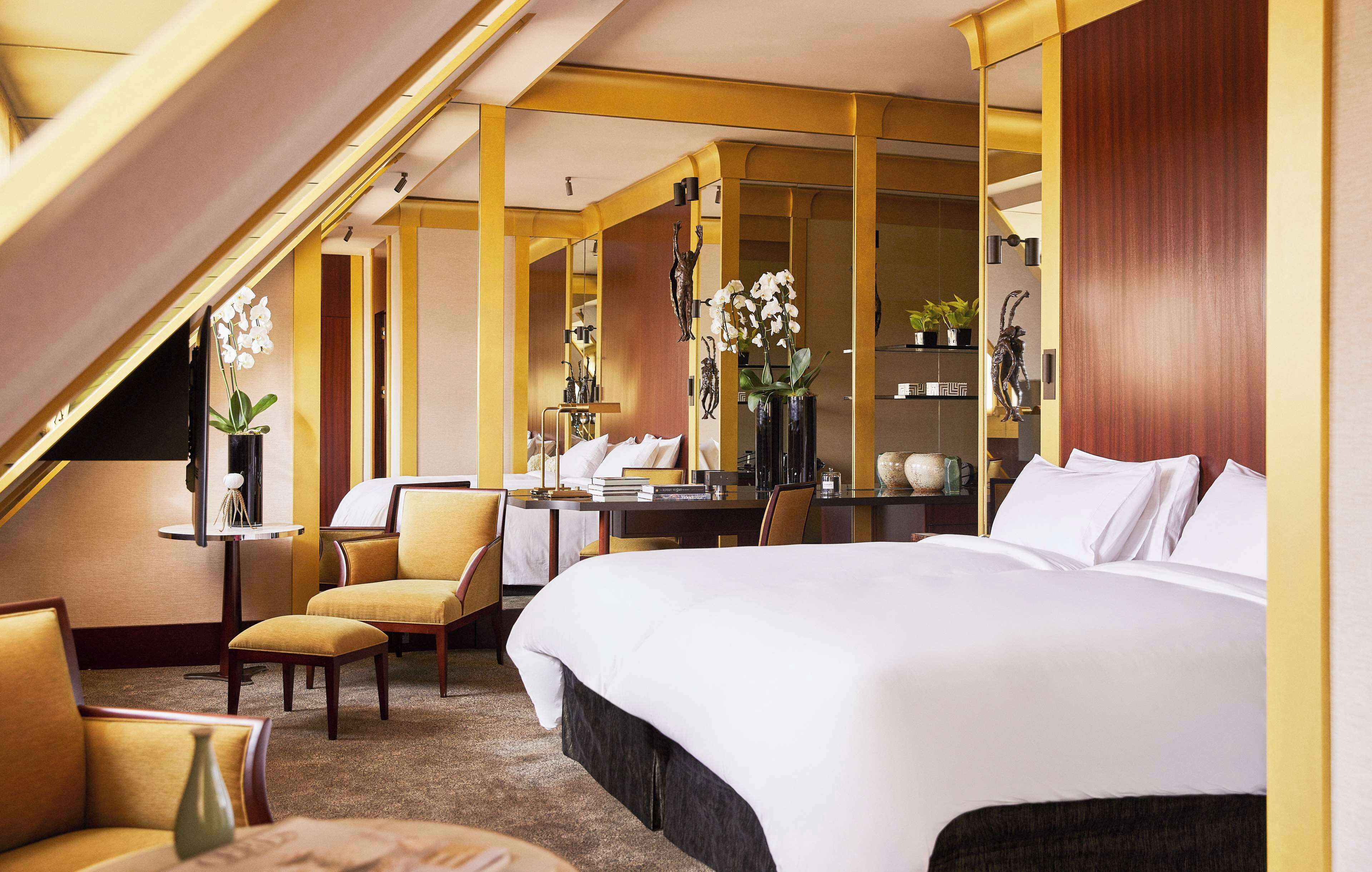Une chambre d’hôtel avec un grand lit, un bureau, deux chaises, une petite table et un miroir.