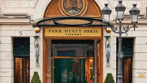 La entrada del Park Hyatt París, con una fachada clásica, un balcón con ornamentada reja de hierro y un cartel grande sobre la entrada.