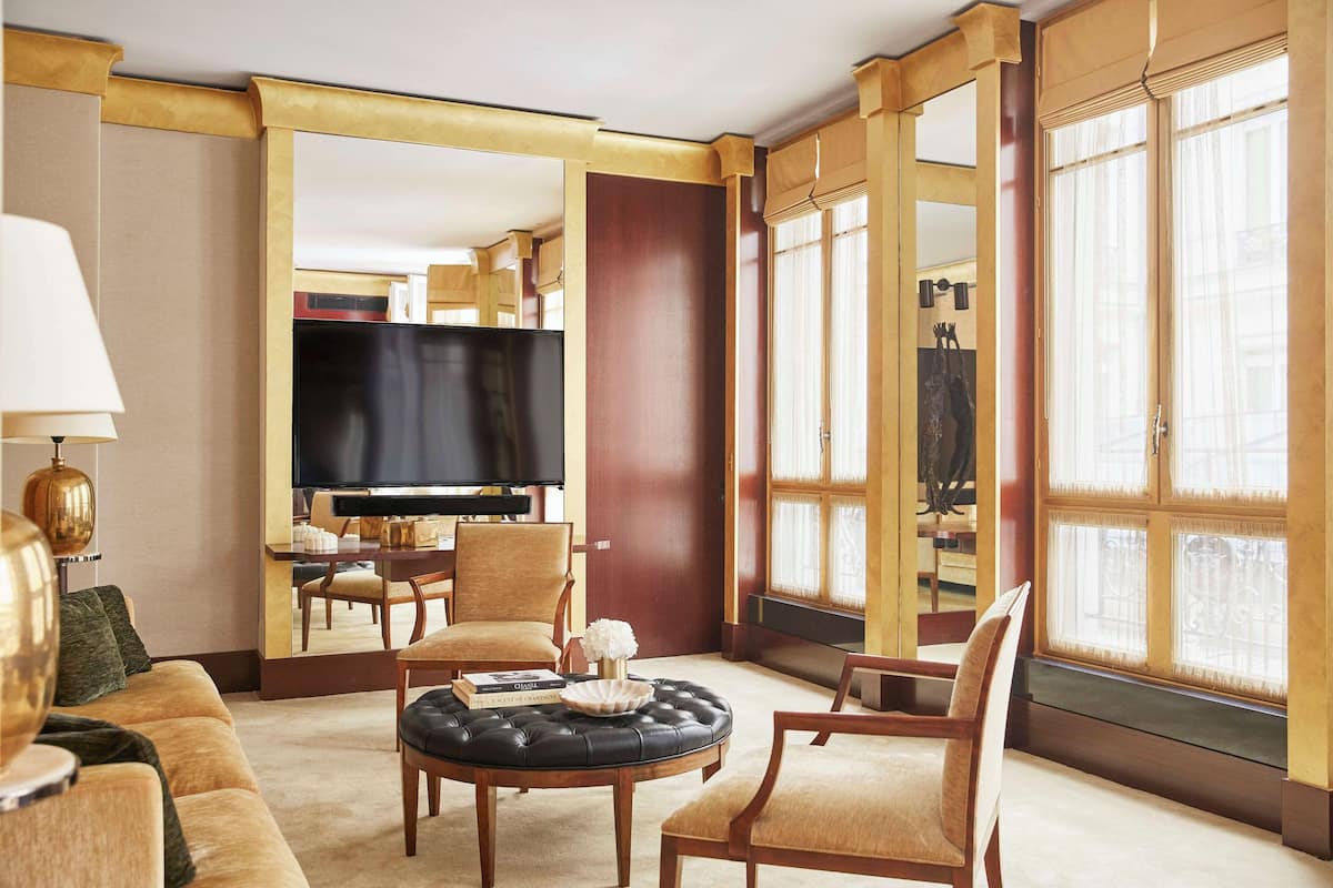 Ein Hotelzimmer mit einem großen Flachbildfernseher, einem runden Couchtisch, einer Couch und einem Essbereich mit Tisch und Stühlen.