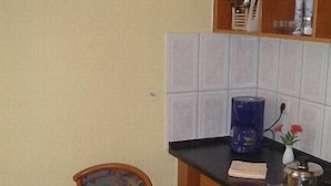 A small kitchen with a wooden table, a chair, and a coffee maker. - Hotel & City Appartements Rothenburger Hof (Dresden)