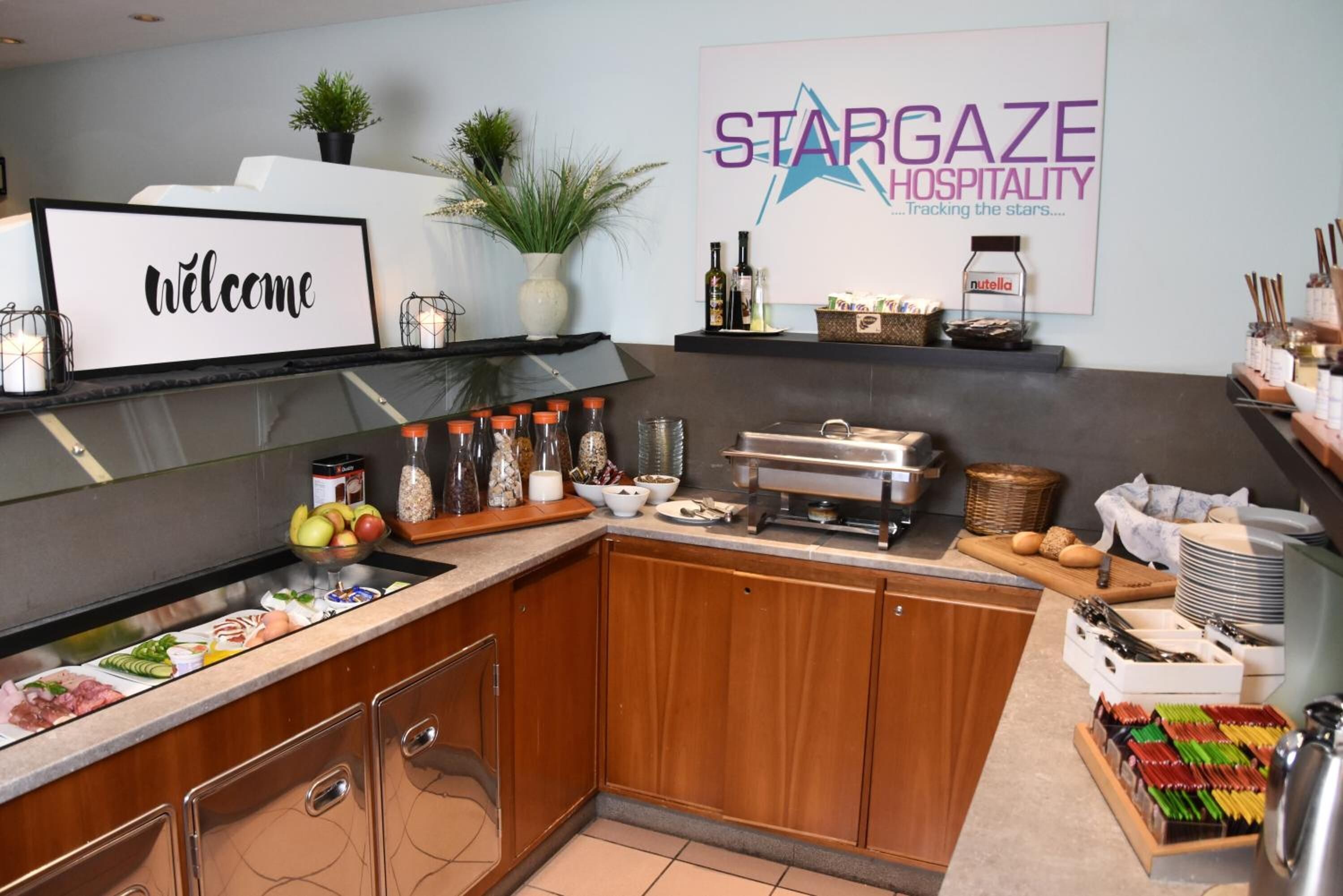 A modern kitchen with a welcome sign, a StarGaze Hospitality sign, and various food items and condiments on the counter.